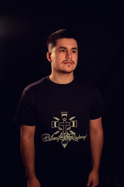 a male model wearing a black blessed and redeemed shirt with a white logo, looking to the right of the camera